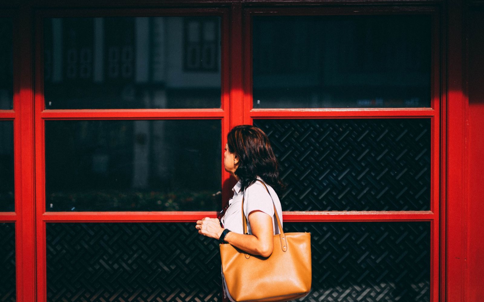 Person walking past a storefront, with face, body, and handbag detected