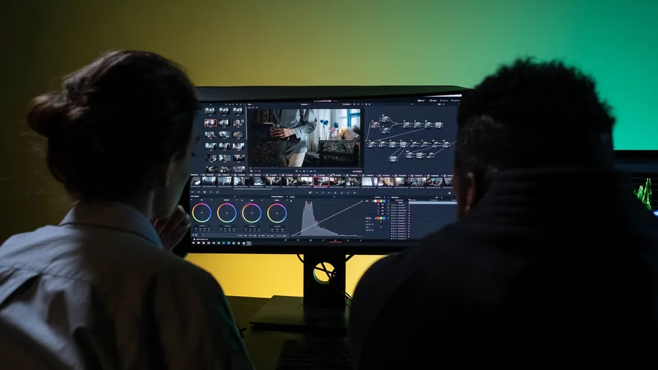 Two editors reviewing a timeline on a studio monitor