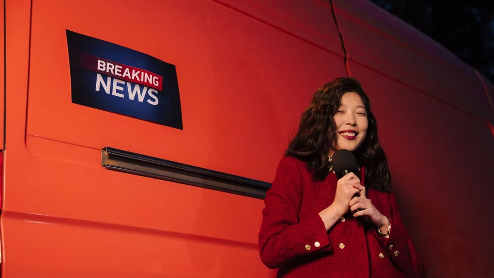 A reporter beside a van carrying a BREAKING NEWS graphic